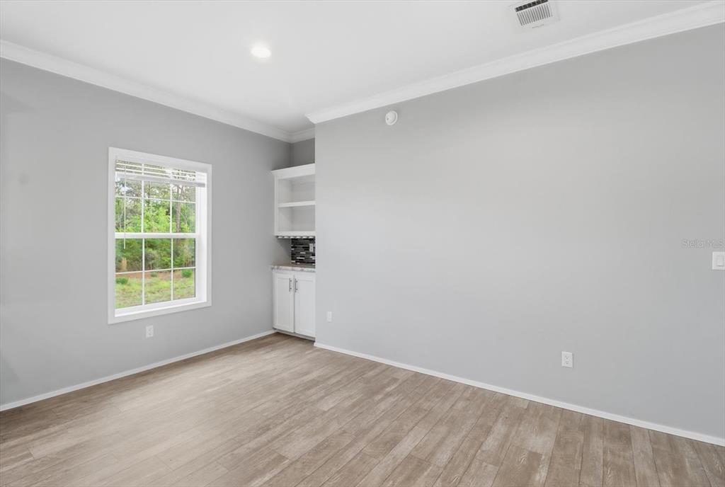 A room with light gray walls, wood-look flooring, a window, and a small built-in cabinet — 6735 W HOMOSASSA TRAIL, HOMOSASSA, FL