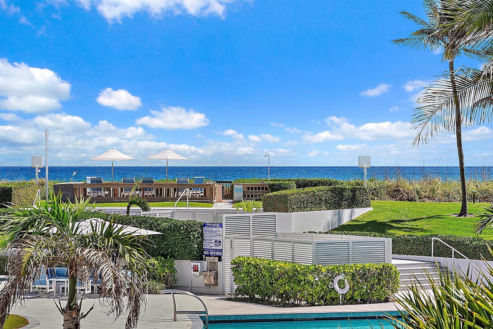 A swimming pool area with lounge chairs, umbrellas, and ocean views under a blue sky — 2600 S Ocean Boulevard # 102w, Palm Beach FL 33480, PALM BEACH, FL