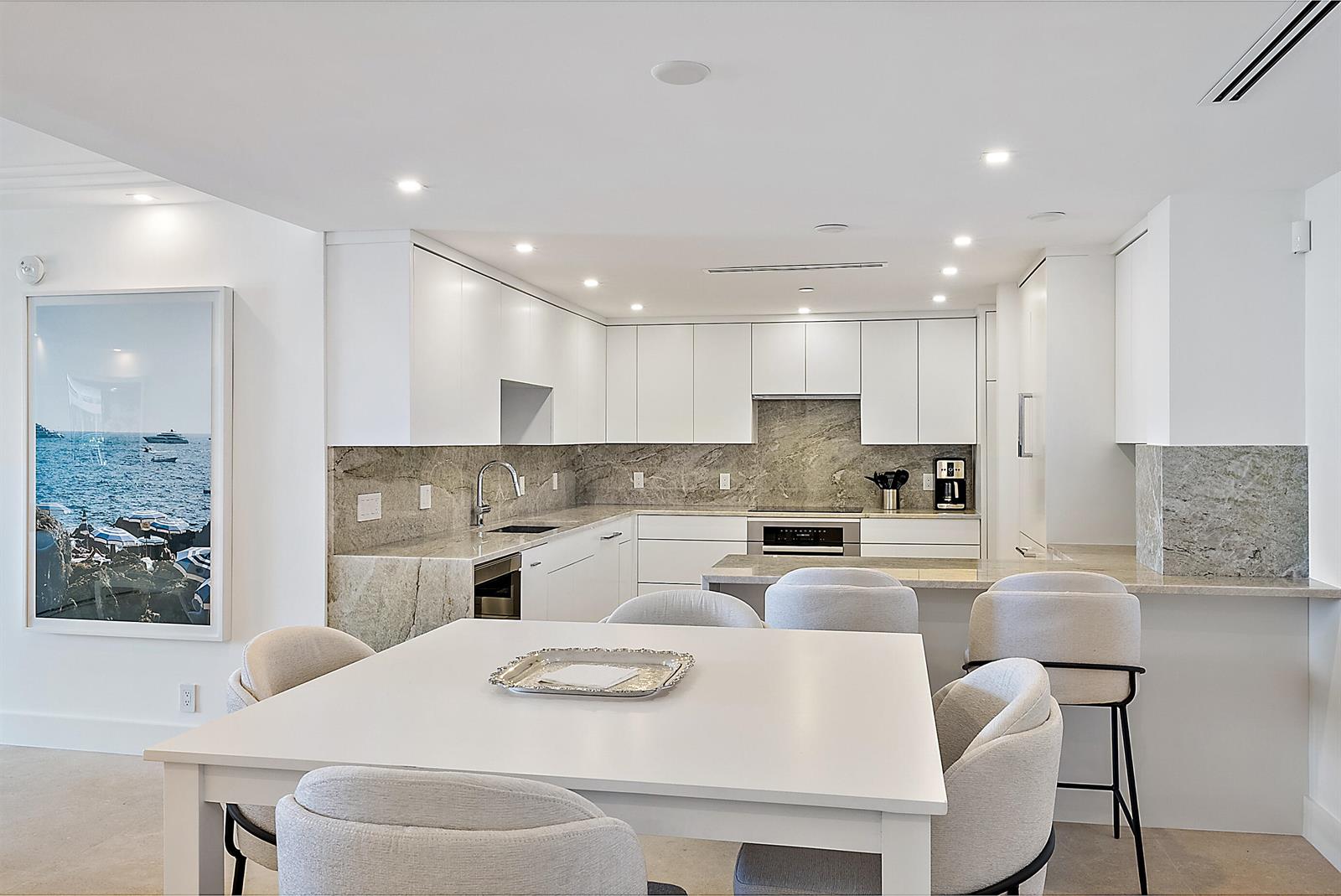 A modern kitchen with white cabinets, stone countertops, and a dining table with upholstered chairs — 2600 S Ocean Boulevard # 102w, Palm Beach FL 33480, PALM BEACH, FL