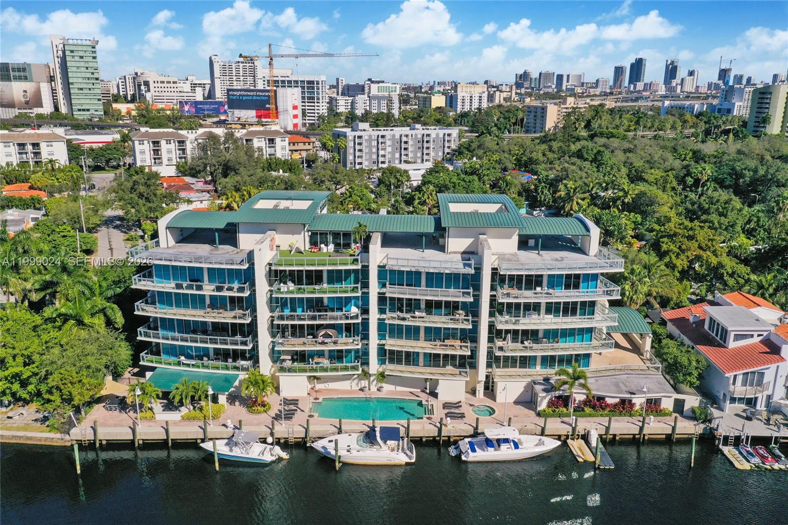 An aerial view of a multi-story waterfront condominium building with a pool and boat slips — 1090 NW N River Dr # 402, Miami FL 33136, MIAMI, FL