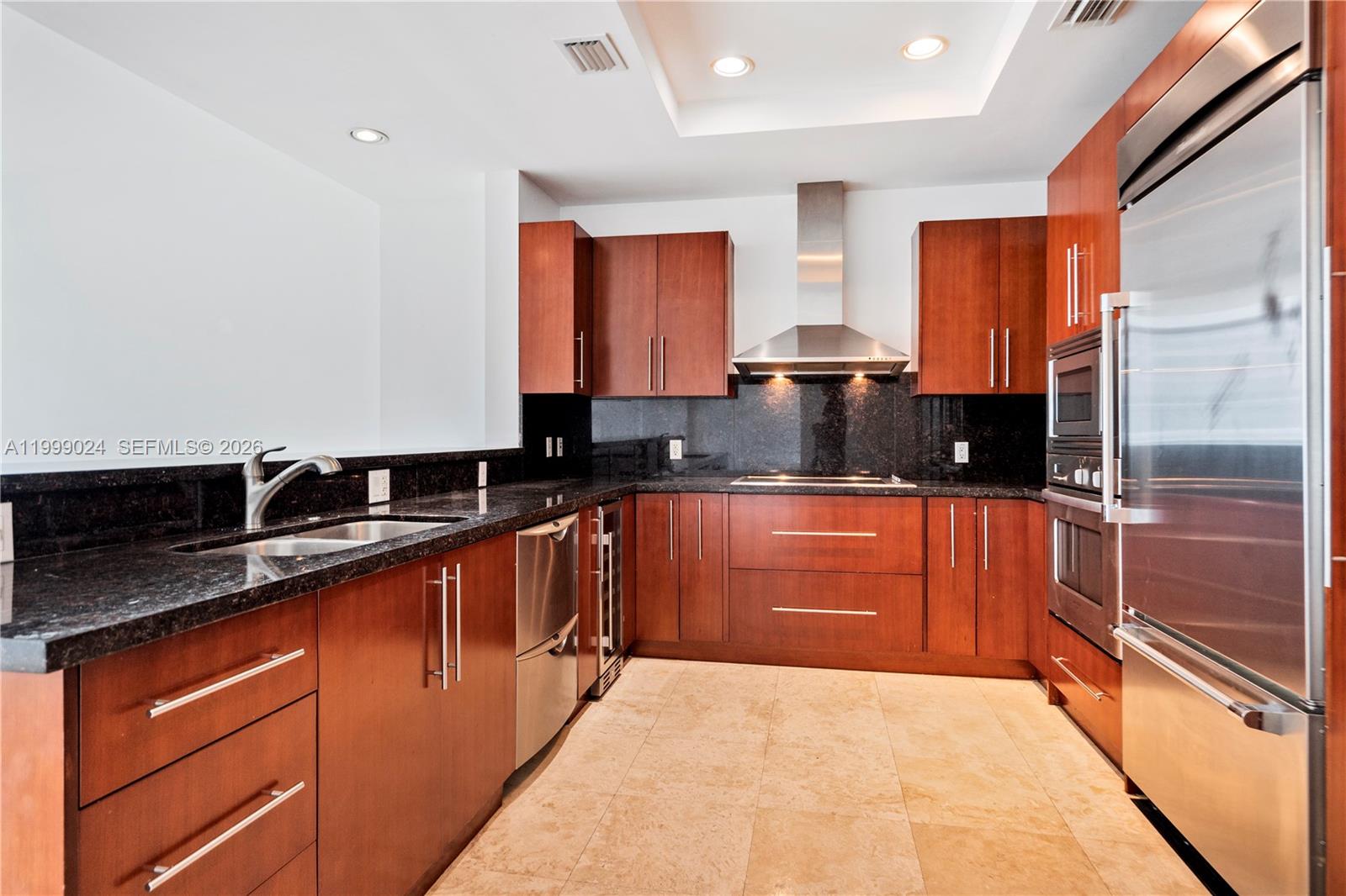 A modern kitchen features dark wood cabinets, black granite countertops, and stainless steel appliances — 1090 NW N River Dr # 402, Miami FL 33136, MIAMI, FL