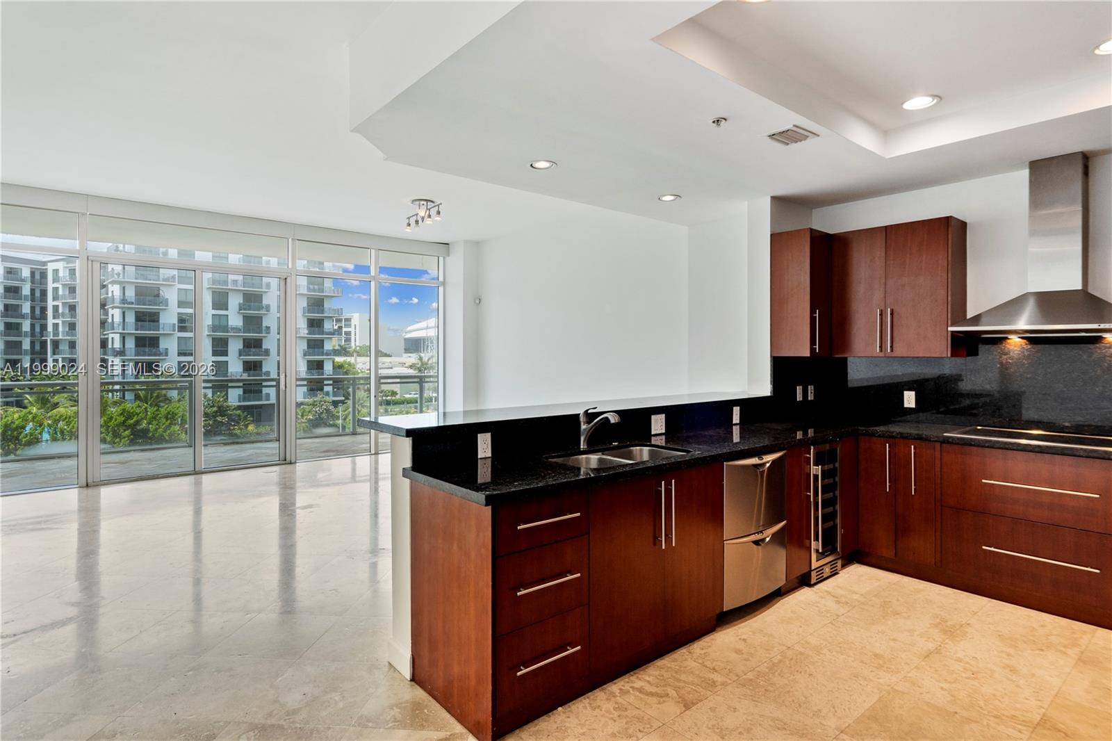 A modern kitchen with dark wood cabinets and black countertops opens to a living area — 1090 NW N River Dr # 402, Miami FL 33136, MIAMI, FL