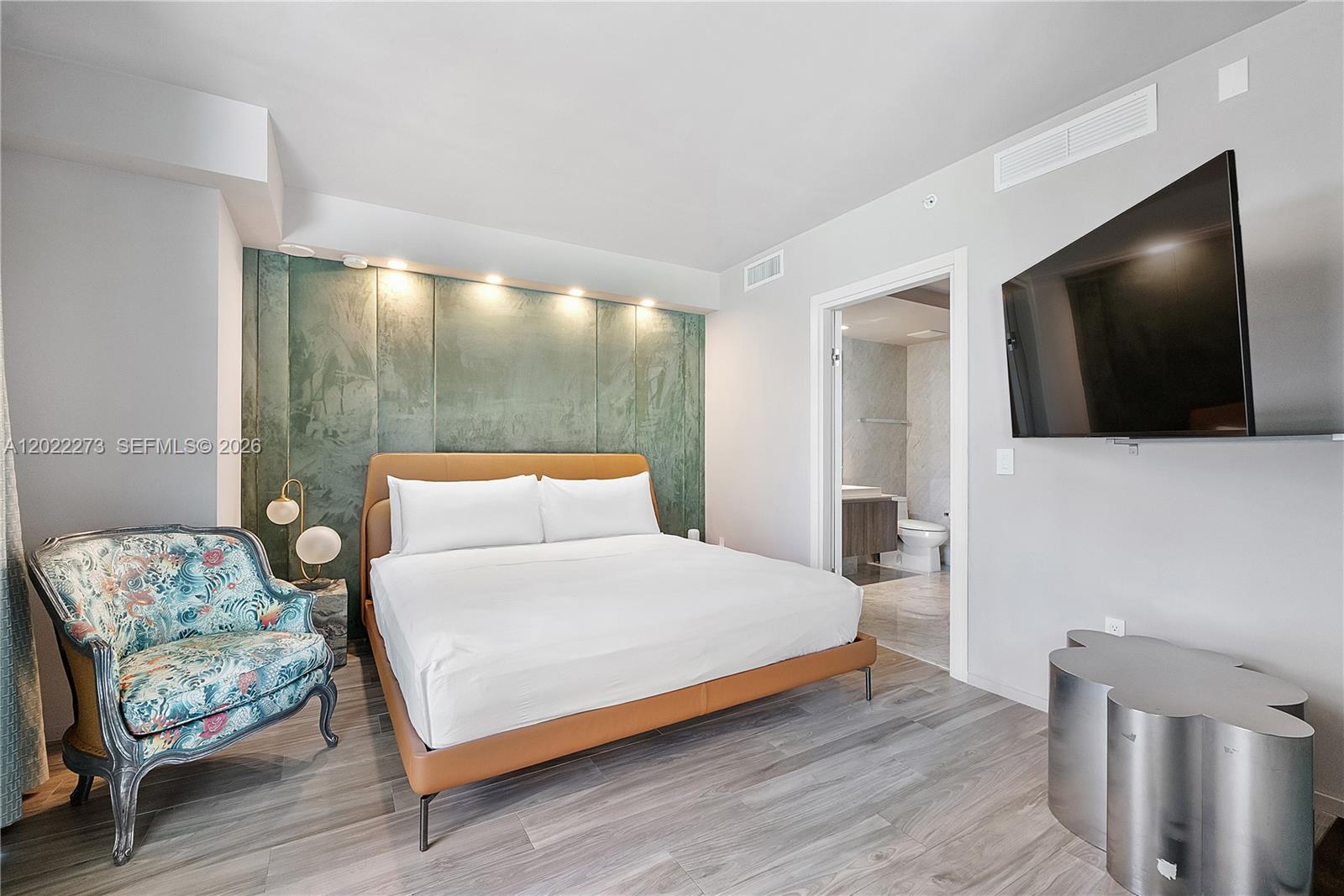 A bedroom features a tan bed, a patterned armchair, and a wall-mounted television — 801 S Miami Ave # 1004, Miami FL 33130, MIAMI, FL