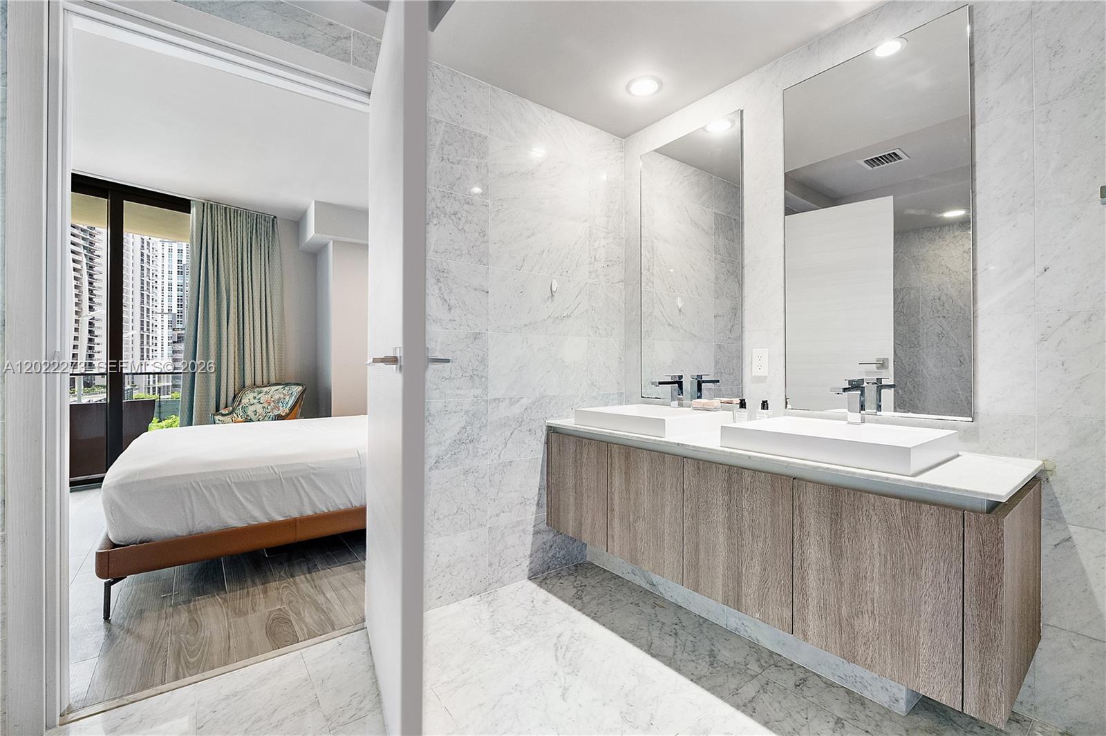 A modern bathroom with a double vanity and marble tile connects to a bedroom — 801 S Miami Ave # 1004, Miami FL 33130, MIAMI, FL