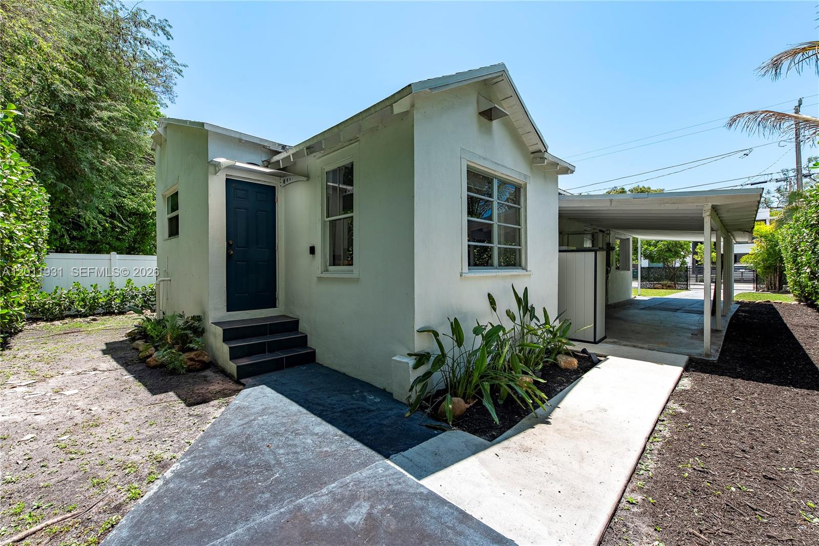 A small white house with a dark blue door, concrete walkway, and attached carport — 3655 Oak Ave # 3655, Miami FL 33133, MIAMI, FL