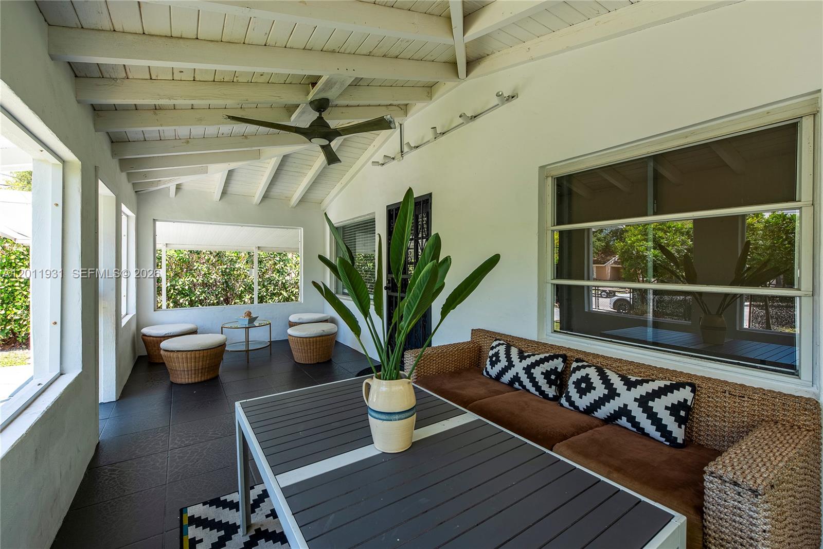 A covered patio features a dark tiled floor, wicker furniture, and a white beamed ceiling — 3655 Oak Ave # 3655, Miami FL 33133, MIAMI, FL