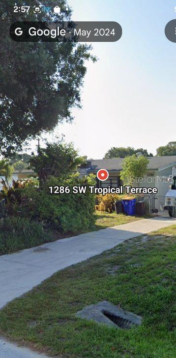 A single-story house with a concrete driveway and a blue trash bin in the yard — 1286 SW TROPICAL TERRACE, STUART, FL
