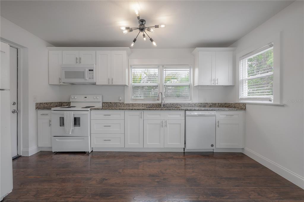 A kitchen with white cabinets, granite countertops, white appliances, and dark wood-look flooring — 405 E CAYUGA STREET, TAMPA, FL