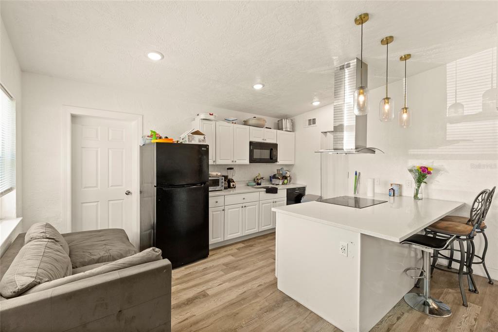 A kitchen features white cabinets, a black refrigerator, a white island, and wood-look flooring — 4821 ELFRIDA AVENUE, SARASOTA, FL