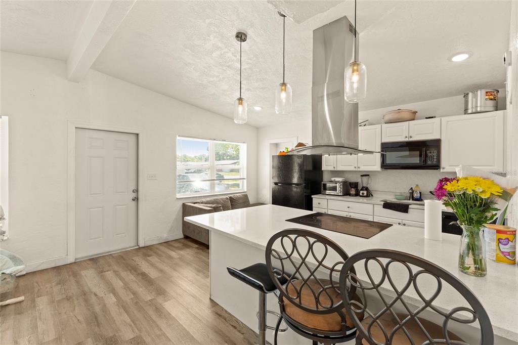 A kitchen features a white island with a cooktop, pendant lights, and white cabinetry — 4821 ELFRIDA AVENUE, SARASOTA, FL