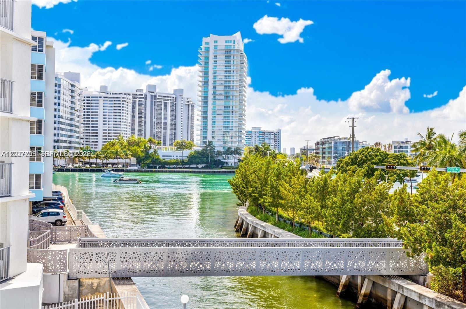 An exterior view shows a canal, a pedestrian bridge, and high-rise buildings under a blue sky — 1674 Bay Rd # 302, Miami Beach FL 33139, MIAMI BEACH, FL
