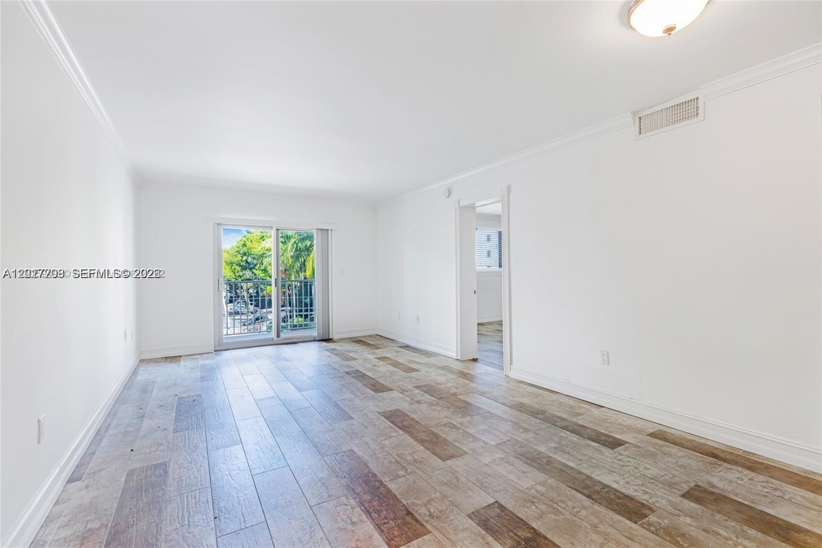 An empty room features white walls, wood-look tile flooring, and a sliding glass balcony door — 1674 Bay Rd # 302, Miami Beach FL 33139, MIAMI BEACH, FL