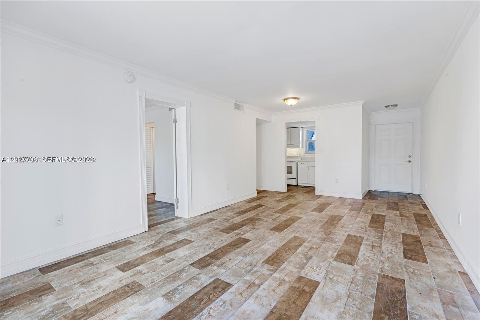An empty room features white walls, crown molding, and wood-look tile flooring — 1674 Bay Rd # 302, Miami Beach FL 33139, MIAMI BEACH, FL