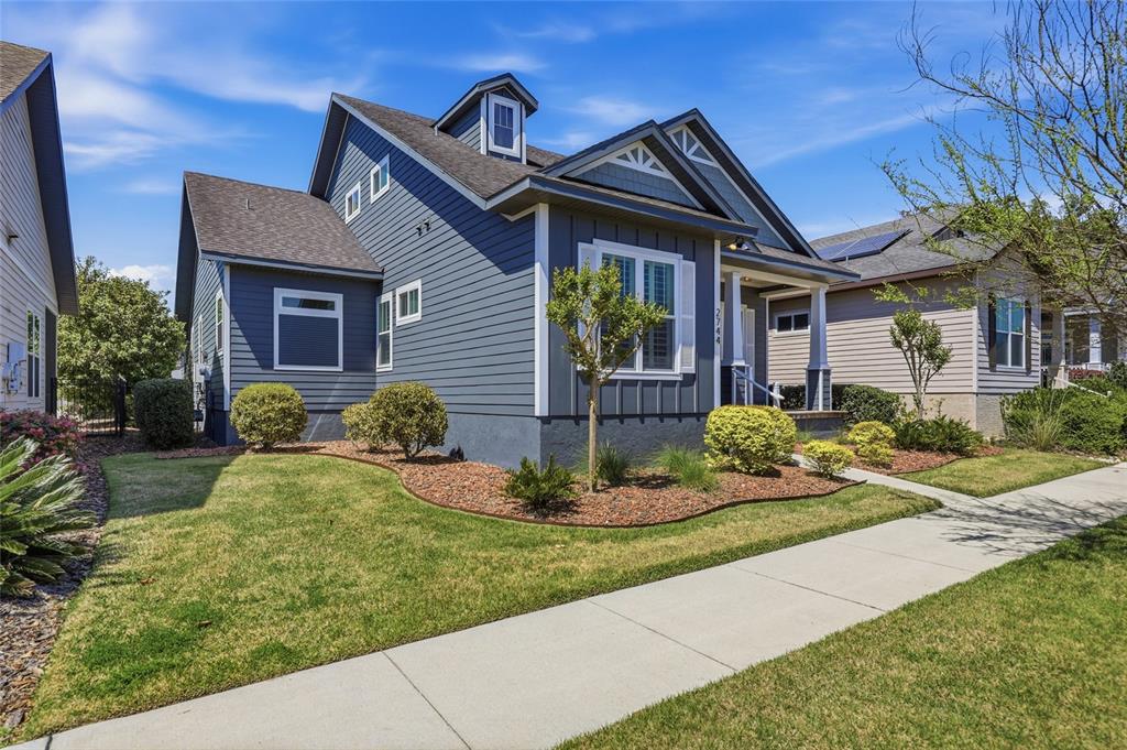 A blue-sided house with a gabled roof and a front porch stands beside a sidewalk — 2744 SW 118TH TERRACE, GAINESVILLE, FL