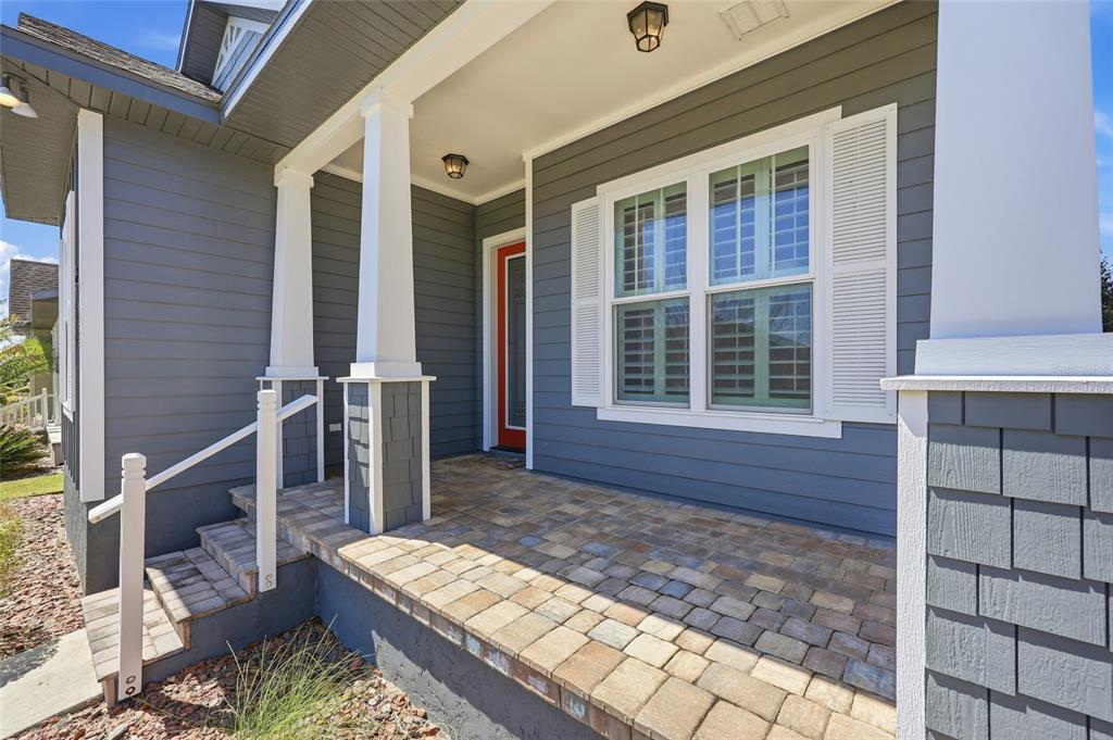 A covered front porch with stone pavers, white columns, and a red front door — 2744 SW 118TH TERRACE, GAINESVILLE, FL