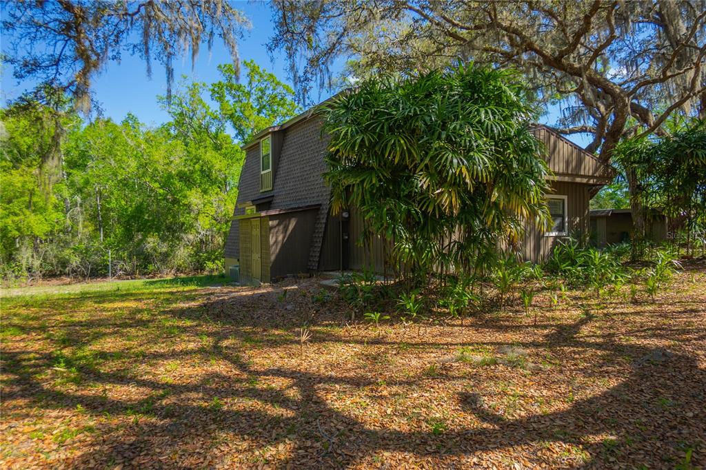 A brown, multi-story house with a sloped roof sits in a wooded, leaf-covered yard — 7536 S BOBCAT POINT, FLORAL CITY, FL