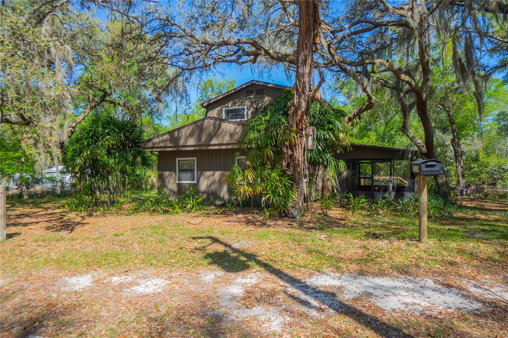 A two-story brown house with vertical siding stands among trees in a wooded yard — 7536 S BOBCAT POINT, FLORAL CITY, FL