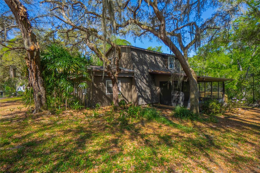 A two-story brown house with a screened porch sits among trees with hanging moss — 7536 S BOBCAT POINT, FLORAL CITY, FL
