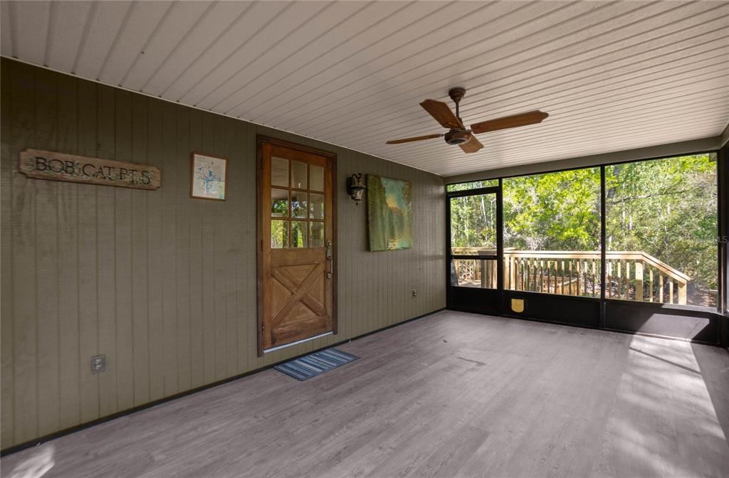 A screened-in porch features wood-paneled walls, a ceiling fan, and a wooden door — 7536 S BOBCAT POINT, FLORAL CITY, FL