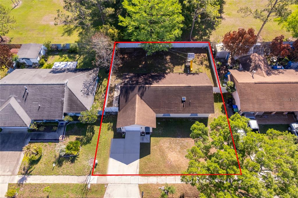 An aerial view shows a single-story house with a brown roof and a fenced backyard — 12141 CAPER STREET, ORLANDO, FL