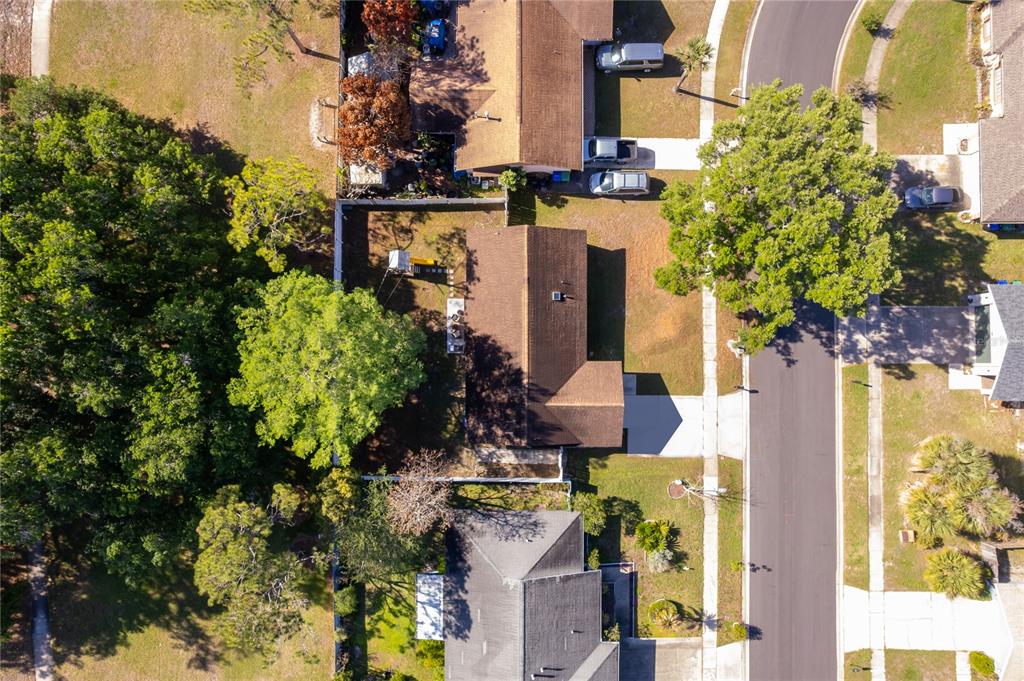 An aerial view shows a residential house with a brown roof, driveway, and backyard — 12141 CAPER STREET, ORLANDO, FL