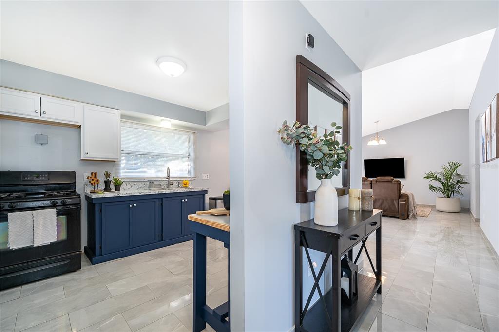 A kitchen with blue cabinets and white uppers opens to a living area with tile floors — 12141 CAPER STREET, ORLANDO, FL