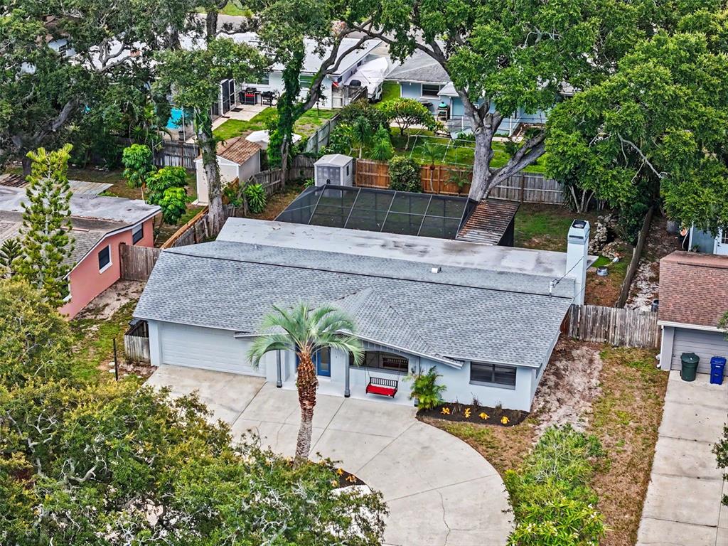 An aerial view shows a single-story house with a gray roof, palm tree, and pool — 57 VENTURA DRIVE, DUNEDIN, FL