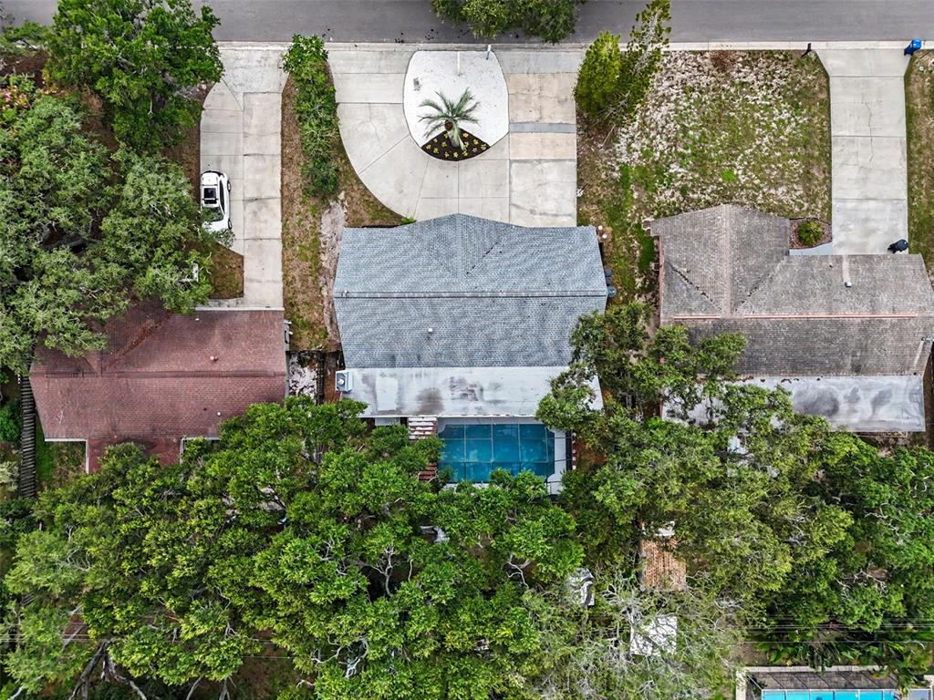 An aerial view shows a house with a pool, large trees, and a circular driveway — 57 VENTURA DRIVE, DUNEDIN, FL