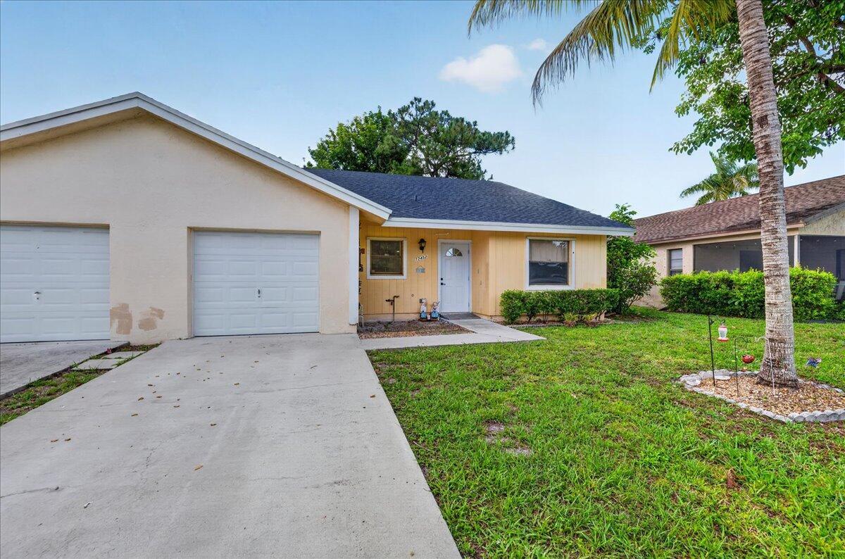 A single-story house with a two-car garage, a light-colored exterior, and a front lawn — 12452 Guilford Way, Wellington FL 33414, WELLINGTON, FL