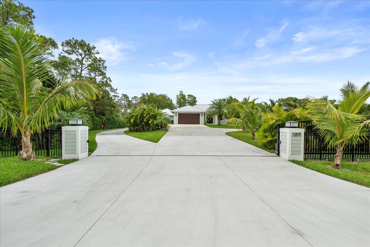 A concrete driveway leads to a house with a garage behind a gated entrance — 12875 157th Street N, Jupiter FL 33478, JUPITER, FL
