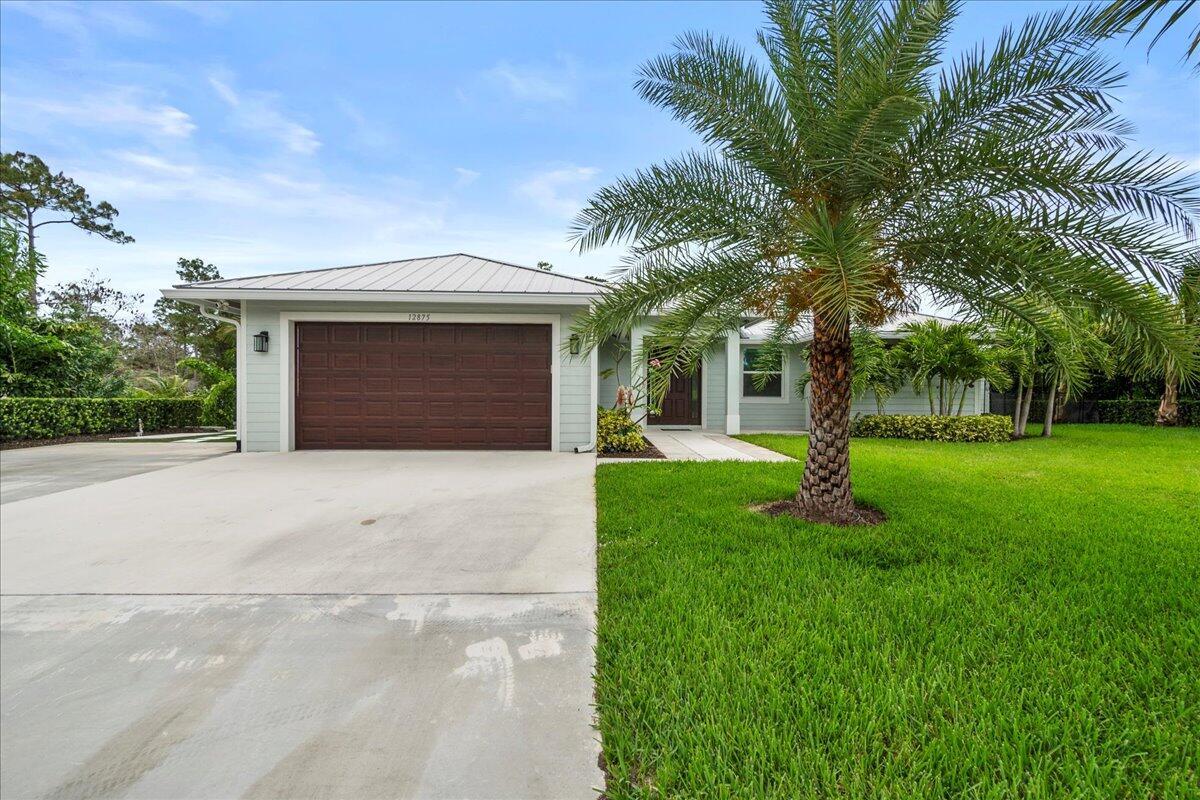 A single-story house with a brown garage door, light siding, and a palm tree — 12875 157th Street N, Jupiter FL 33478, JUPITER, FL