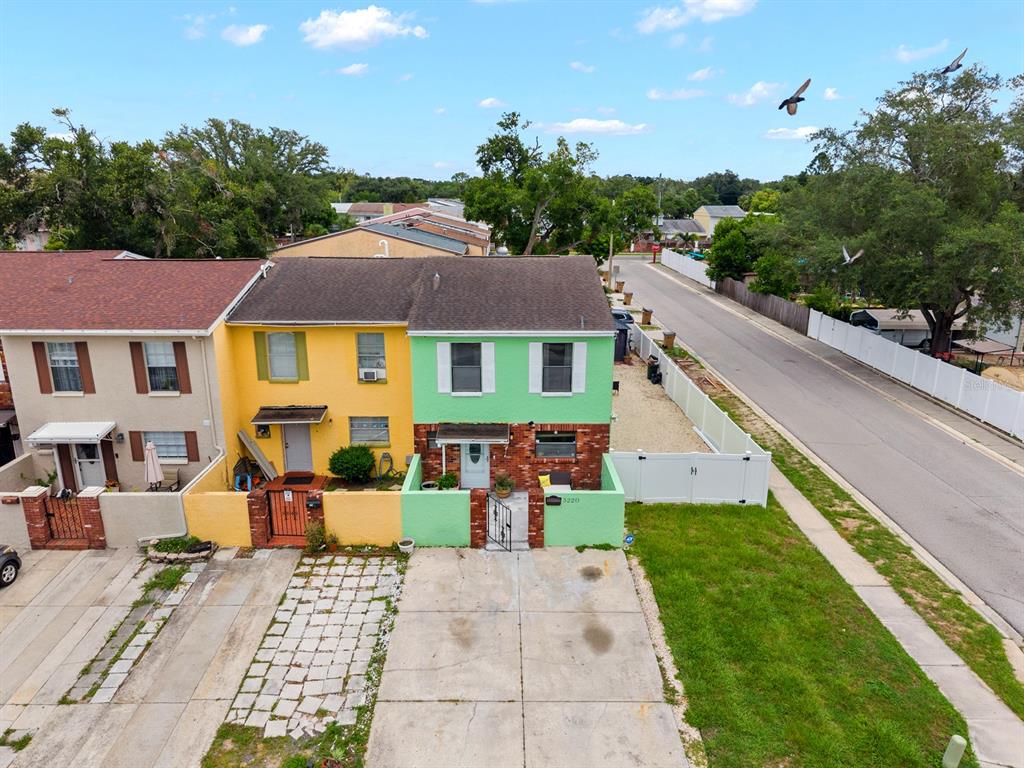 An aerial view shows two adjacent townhomes with yellow and green facades and concrete driveways — 5220 BLANE DRIVE, TEMPLE TERRACE, FL