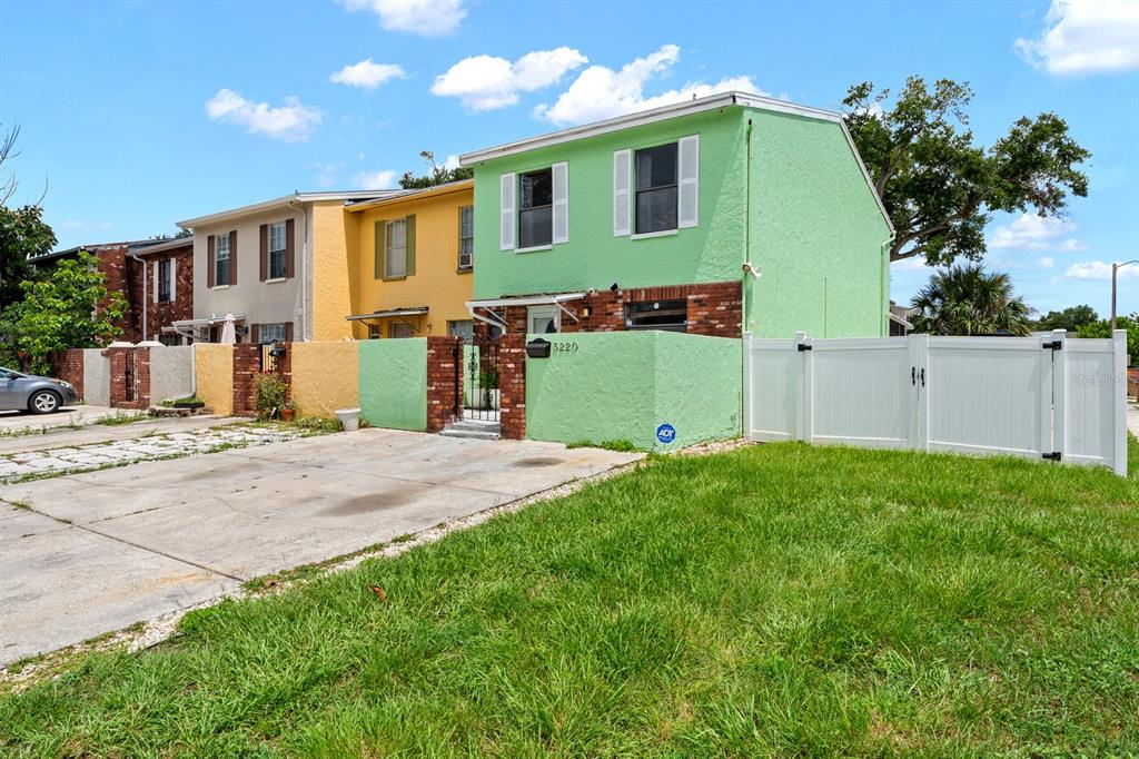 A bright green two-story townhouse with a concrete driveway and a white vinyl fence — 5220 BLANE DRIVE, TEMPLE TERRACE, FL