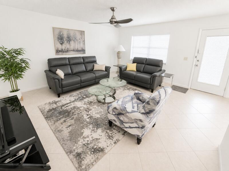 A living room features gray leather sofas, a patterned armchair, and a glass coffee table — 567 Burgundy L, Delray Beach FL 33484, DELRAY BEACH, FL