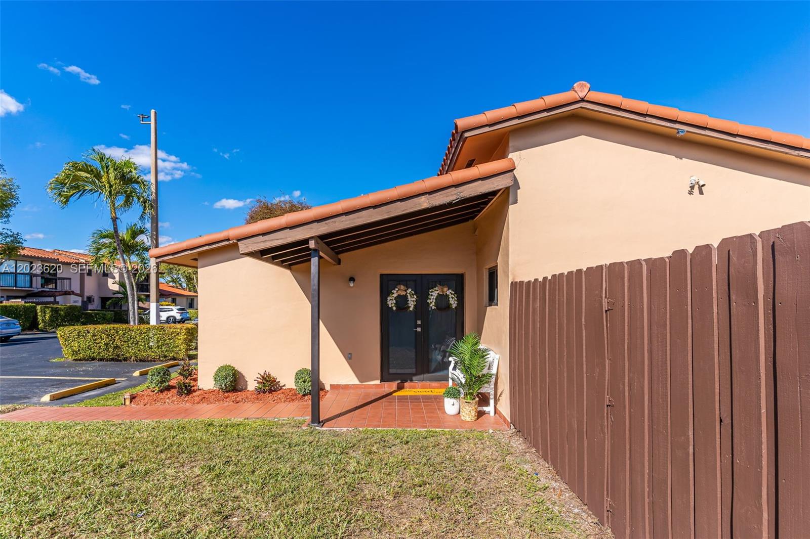 The exterior of a single-story home features a tiled entryway, double doors, and wooden fencing — 3815 SW 82nd Ave # 41, Miami FL 33155, MIAMI, FL