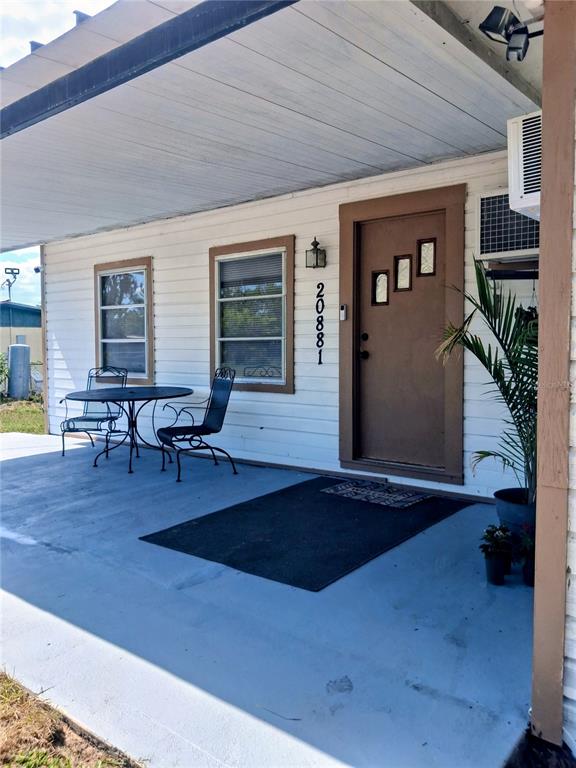 A covered porch features a small table with two chairs and a brown front door — 20881 SE 142ND PLACE, UMATILLA, FL