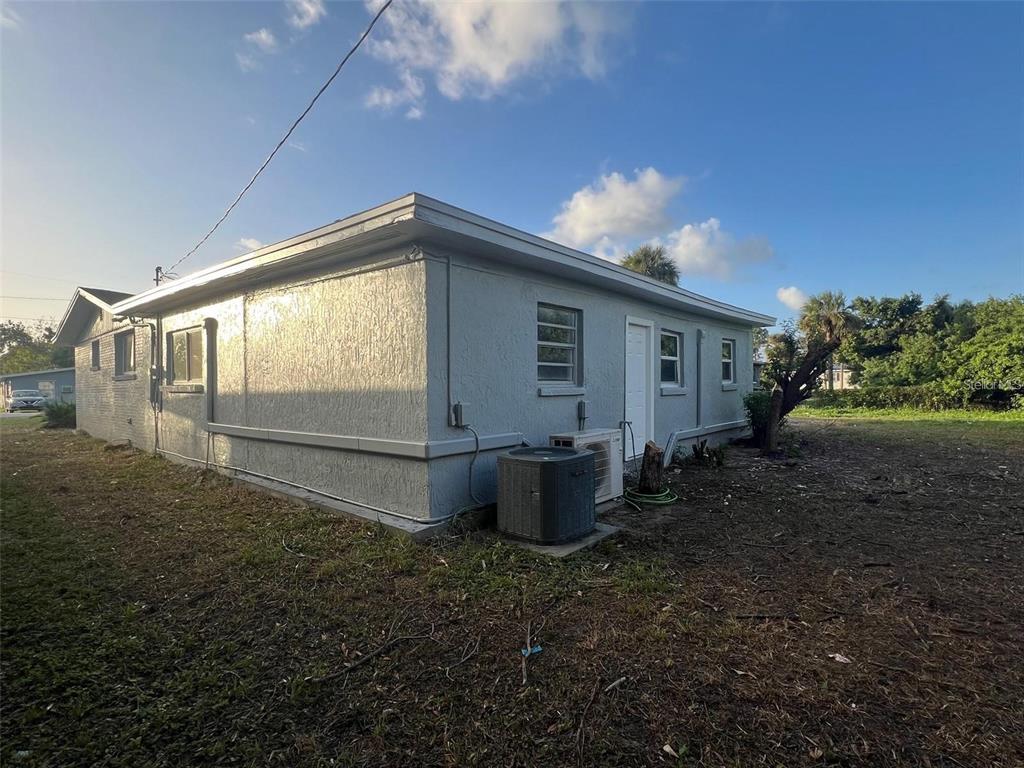 The exterior of a light gray, single-story house with a flat roof and HVAC unit — 614 PAW PAW STREET, COCOA, FL