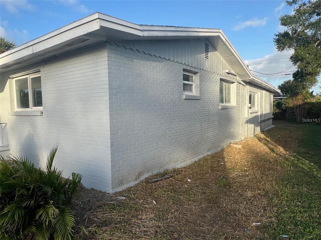 A side view of a gray painted brick house with a gabled roof and windows — 614 PAW PAW STREET, COCOA, FL