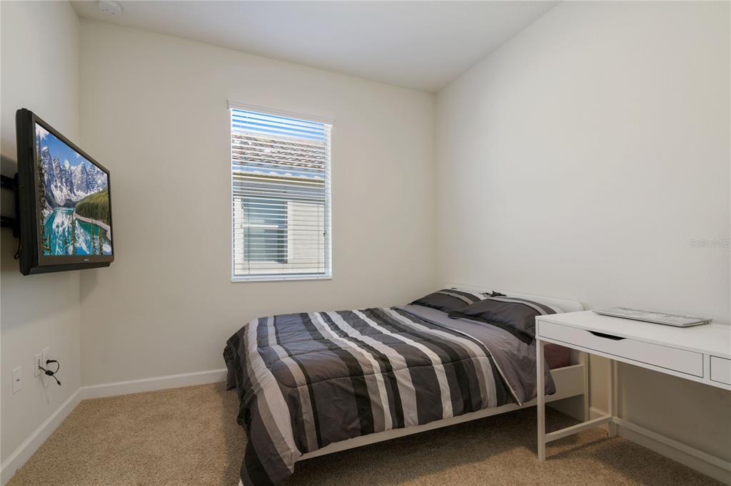 A bedroom with beige carpet, a bed, a desk, and a wall-mounted television — 2157 LAKE SIDE AVENUE, DAVENPORT, FL