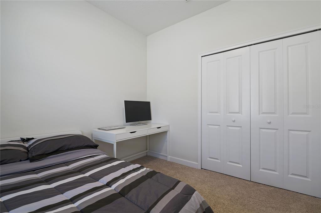 A bedroom features a bed with a striped comforter, a white desk, and closet doors — 2157 LAKE SIDE AVENUE, DAVENPORT, FL