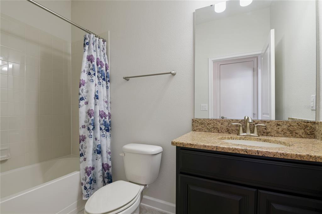 A bathroom features a dark wood vanity with a granite countertop, a toilet, and a tub — 2157 LAKE SIDE AVENUE, DAVENPORT, FL