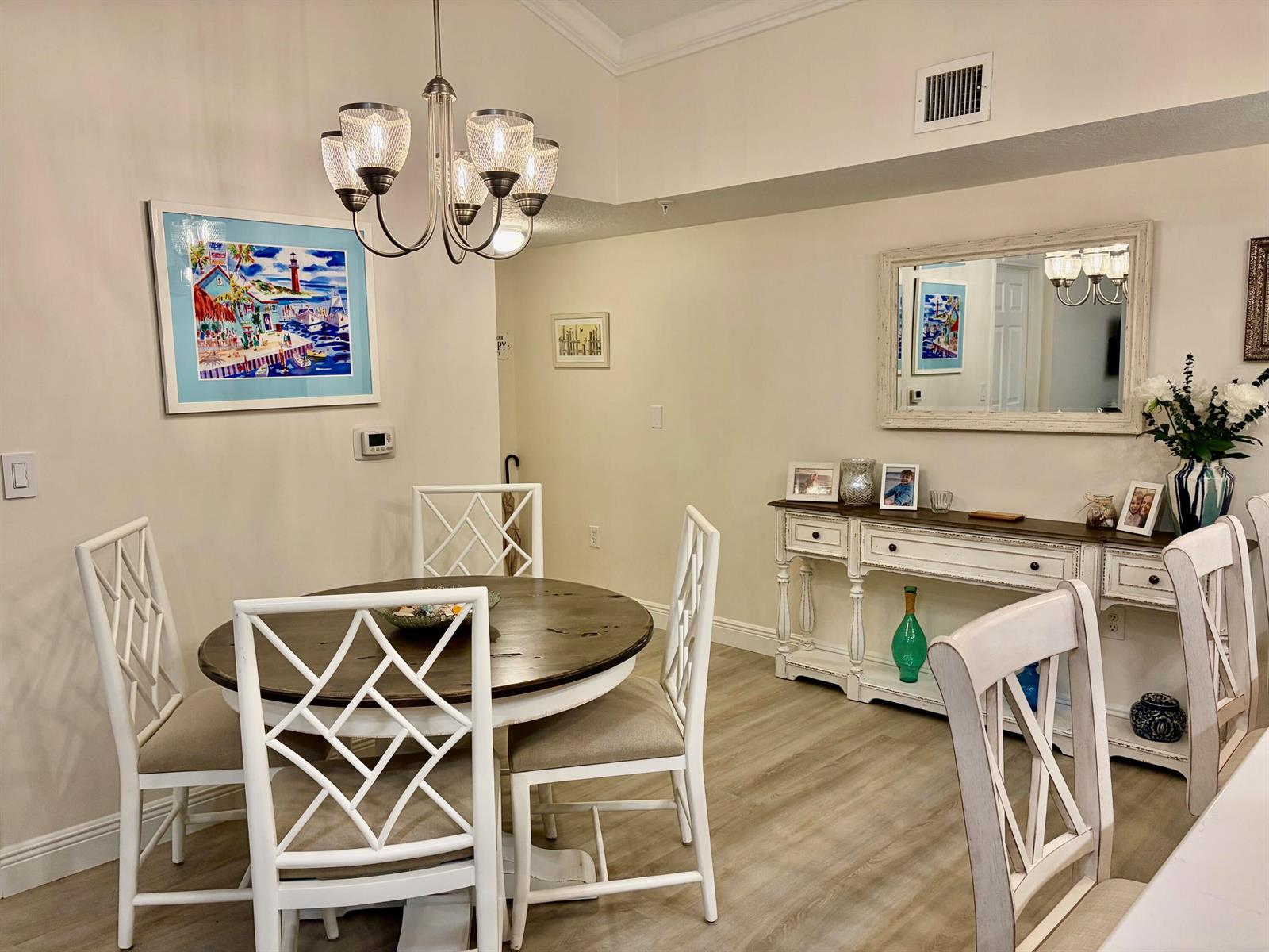 A dining room features a round wooden table, white lattice-back chairs, and a matching console table — 242 Village Boulevard # 2304, Tequesta FL 33469, TEQUESTA, FL