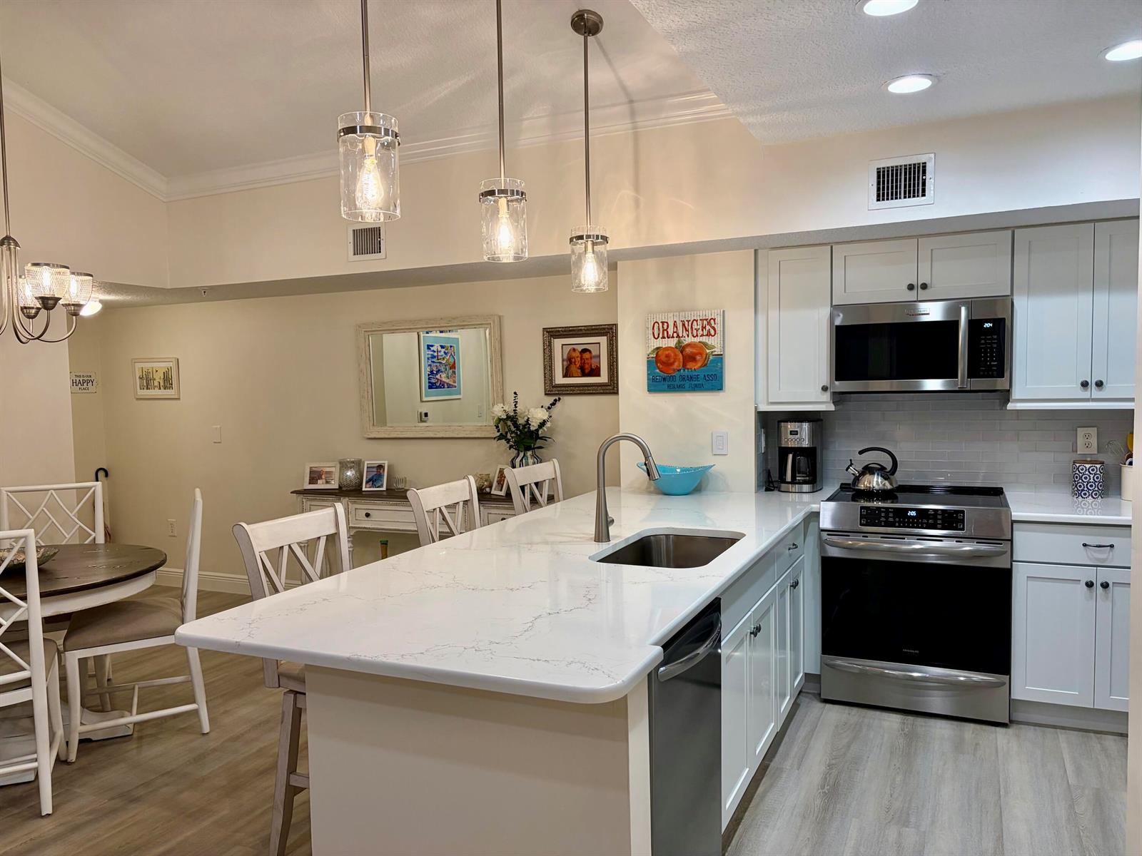 A kitchen with white cabinets, a quartz island countertop, stainless steel appliances, and pendant lighting — 242 Village Boulevard # 2304, Tequesta FL 33469, TEQUESTA, FL