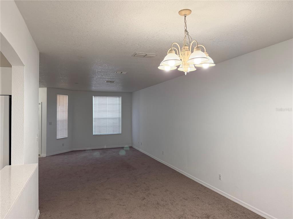 An empty room features beige carpeting, white walls, and a multi-light chandelier — 642 CAPTIVA CIRCLE UNIT 642, KISSIMMEE, FL