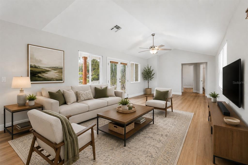 A living room features a vaulted ceiling, light wood flooring, and neutral-toned furniture — 7745 WESTMORELAND DRIVE, SARASOTA, FL