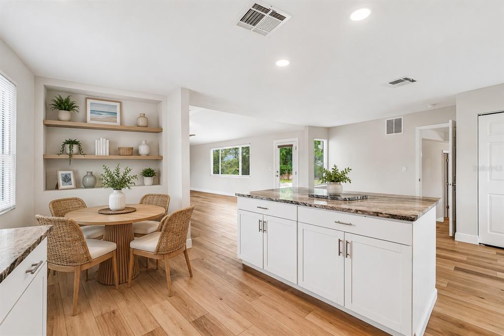 A kitchen with a white island, wood flooring, and a dining area with built-in shelves — 7745 WESTMORELAND DRIVE, SARASOTA, FL