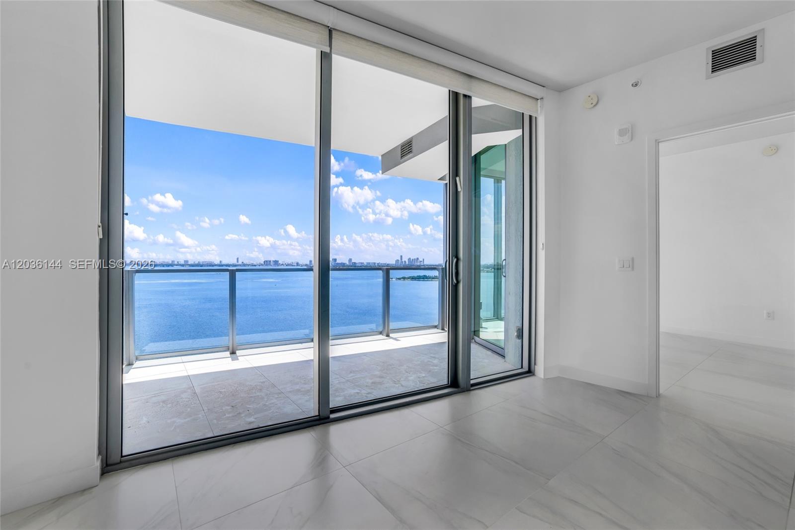 A bright room with white tile floors features large sliding glass doors opening to a balcony — 2900 NE 7th Ave # 1806, Miami FL 33137, MIAMI, FL