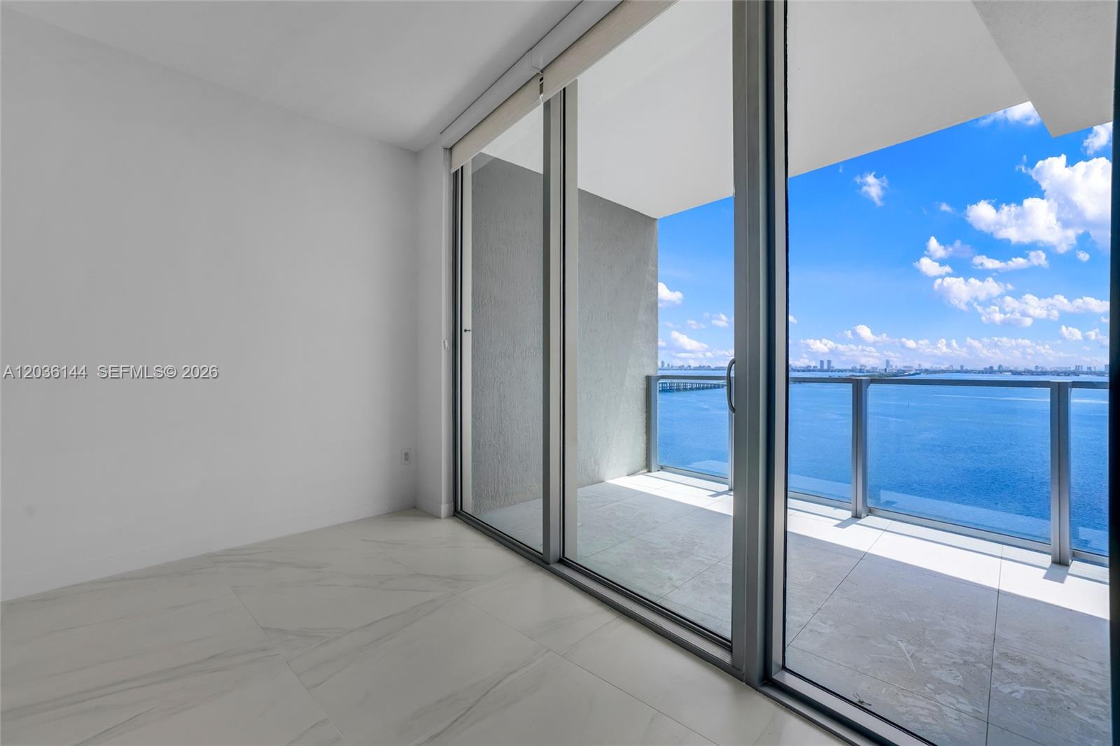 An empty room with white marble floors features large sliding glass doors opening to a balcony — 2900 NE 7th Ave # 1806, Miami FL 33137, MIAMI, FL