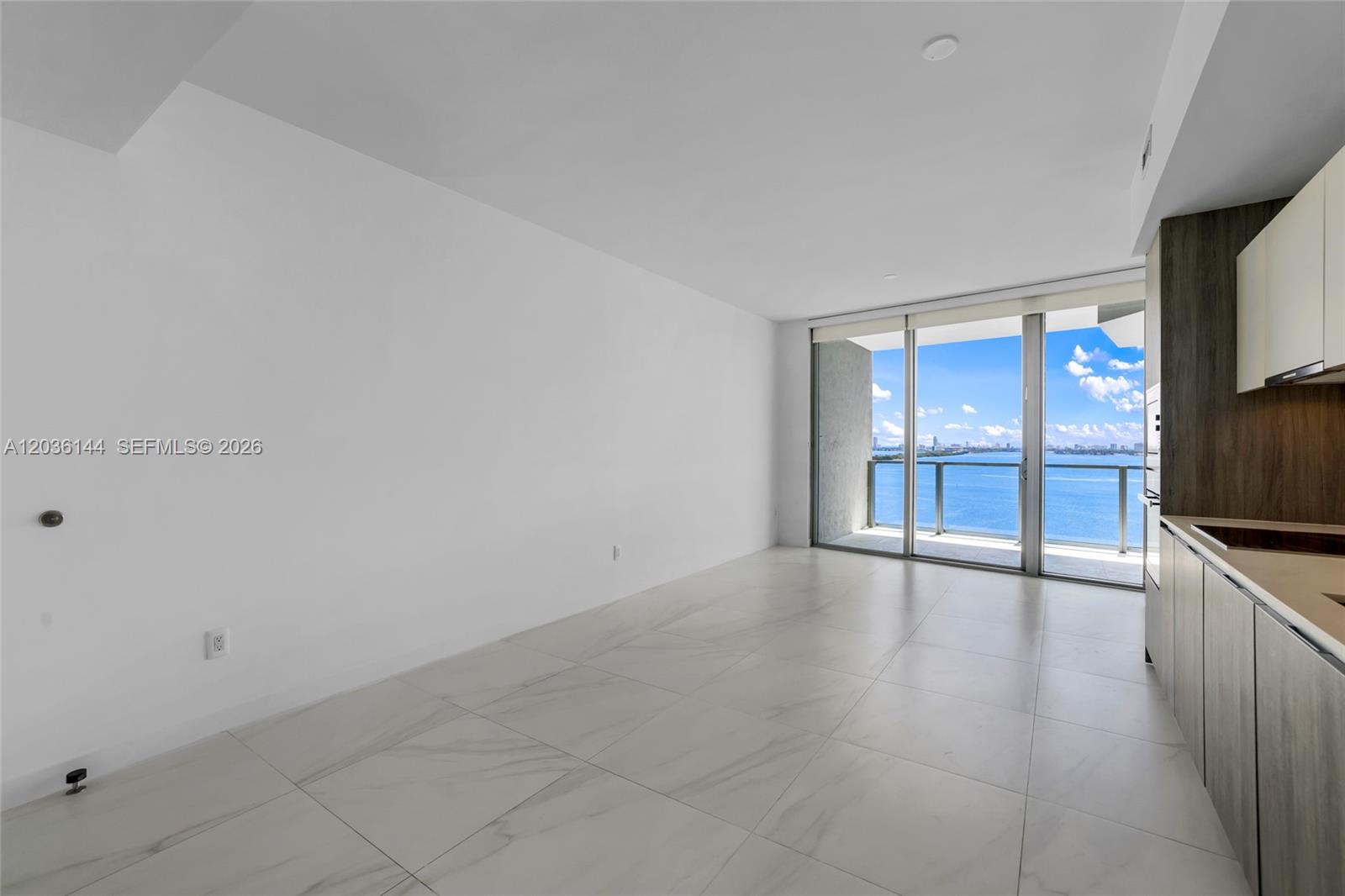 An open-concept living area features white tile floors, a modern kitchen, and a balcony view — 2900 NE 7th Ave # 1806, Miami FL 33137, MIAMI, FL