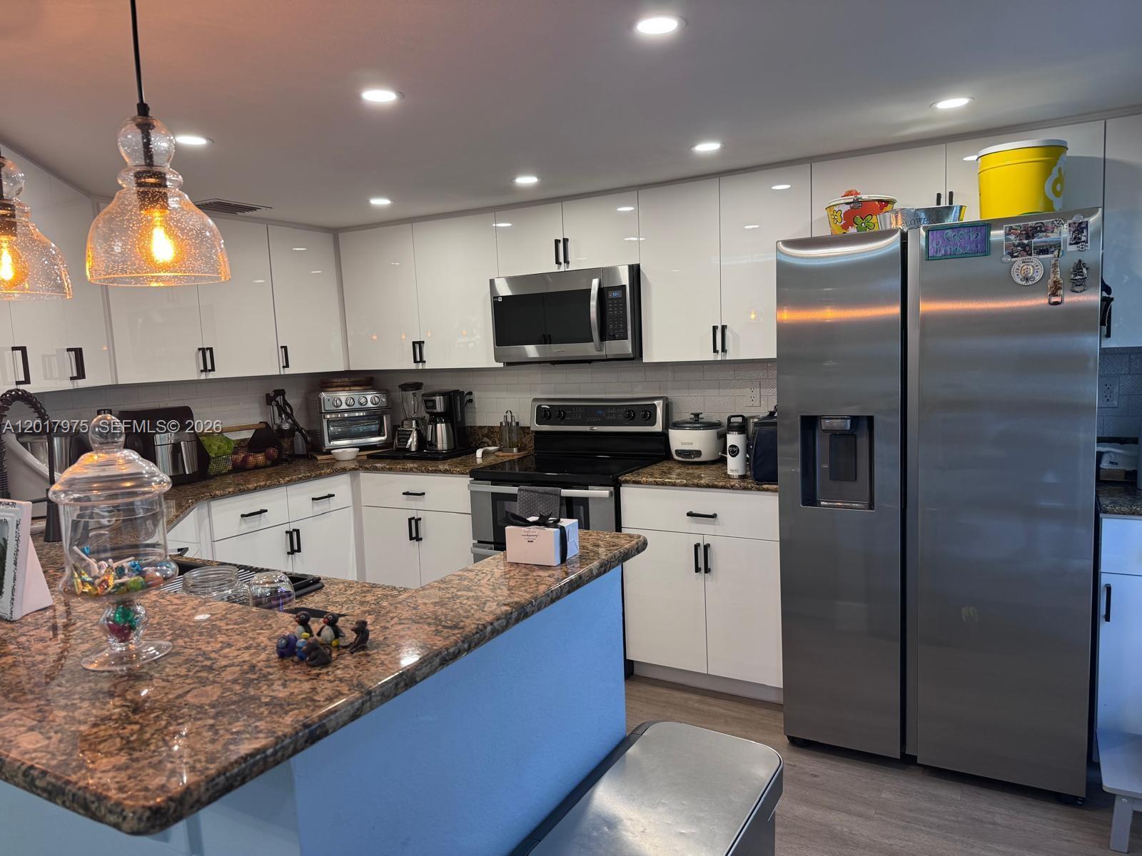 A kitchen features white cabinets, stainless steel appliances, and brown granite countertops — 8851 NW 110th Pl # 1407, Doral FL 33178, DORAL, FL